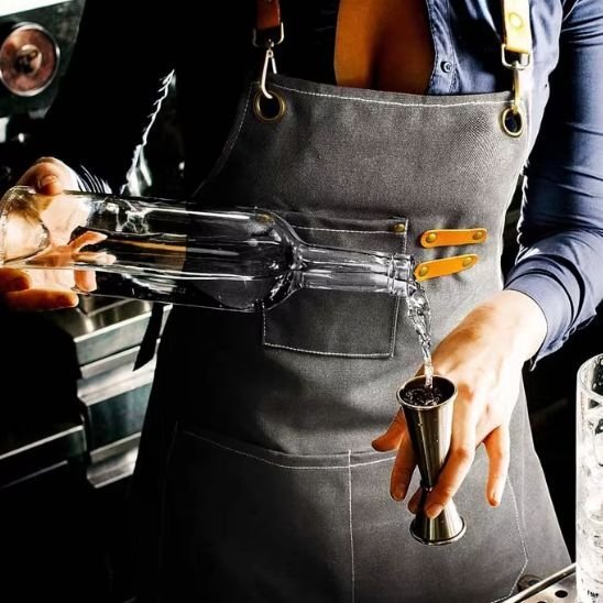 tablier de cuisine gris femme avec bouteille et verre doseur a la main