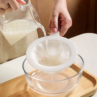 bol en verre sur plateau carre en bois comptoir cuisine blanc filtrant liquide avec passoire 