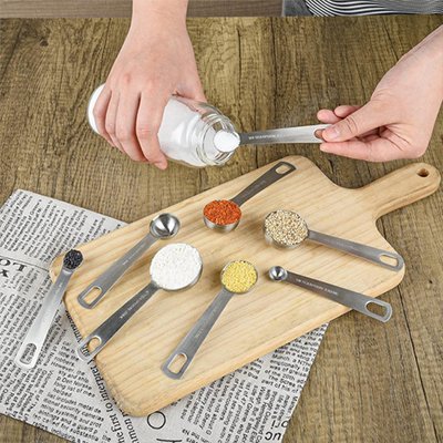 cuilleres doseuses de sel sur planche de bois avec plusieurs ingredients comptoir papier journal