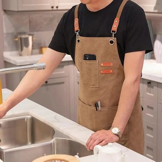 cuisine blanche et homme portant tablier de cuisine brun avec chandail noir