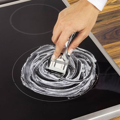 main femme avec grattoir plaque induction nettoyage degat blanc comptoir en bois