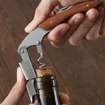 main homme avec tire bouchon ouvrant bouteille de vin